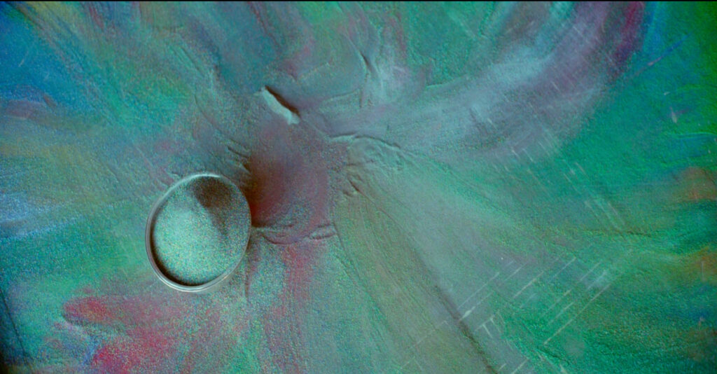Coloured grains of sand and a bowl after the destruction of the Mandala.